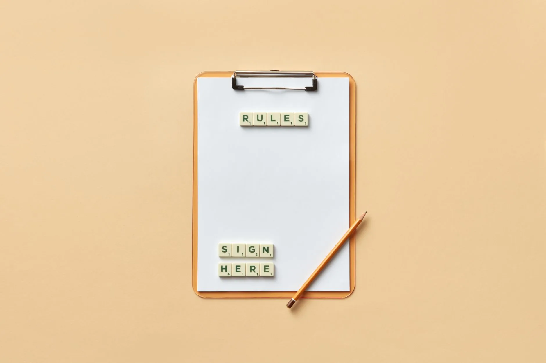 A clipboard with tiles spelling out rules and sign here, next to a pencil.