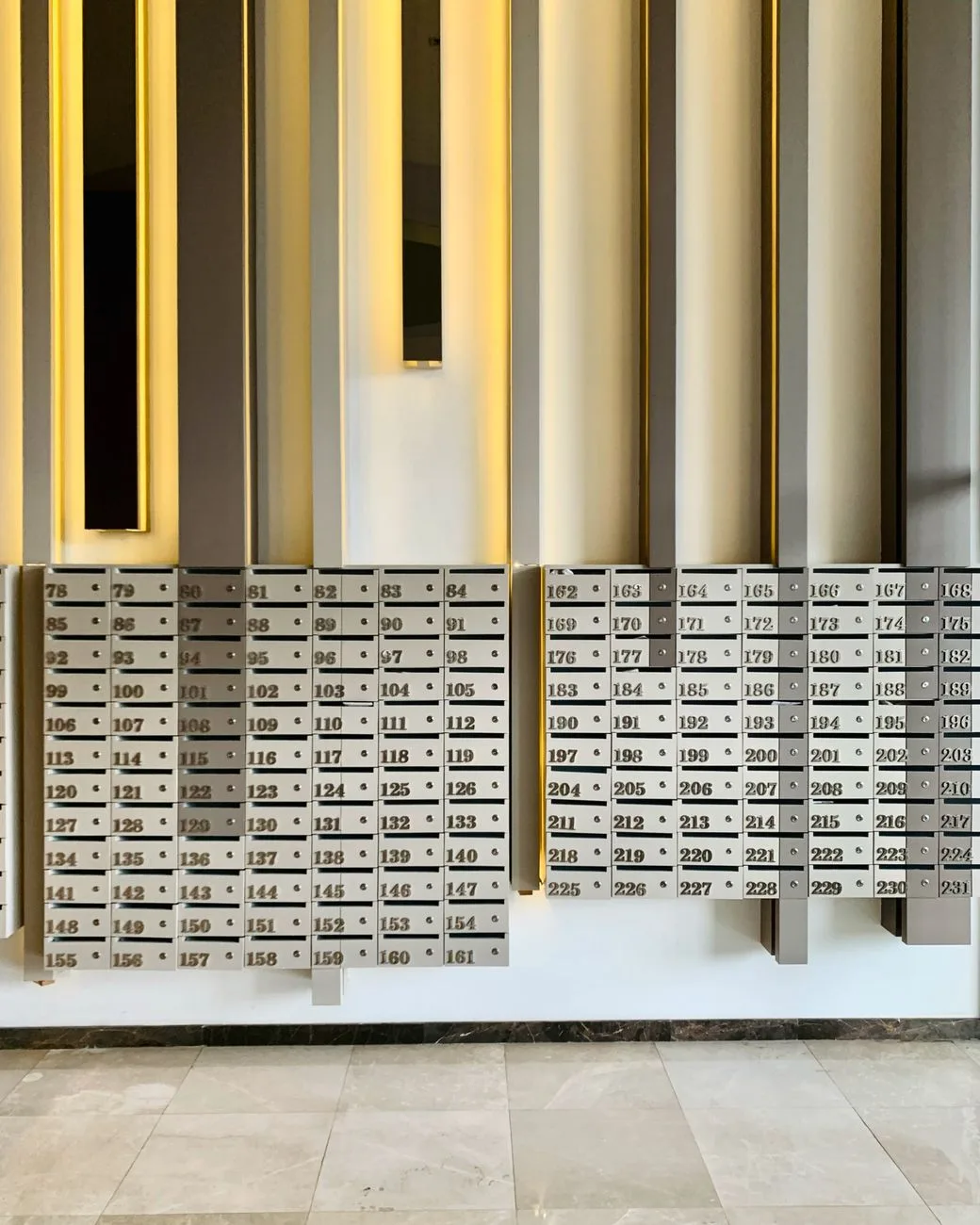 Wall of numbered mailbox slots in a residential apartment building lobby.