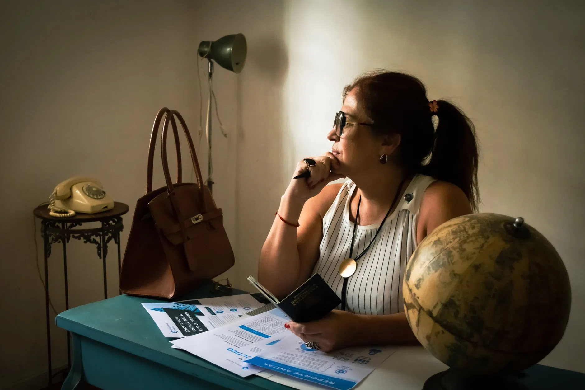 A vintage office desk with a globe, travel documents, and a classic phone.