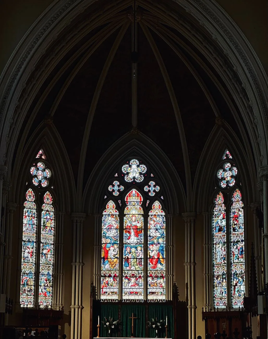 Stained glass windows showcasing religious themes inside a Gothic-style church.
