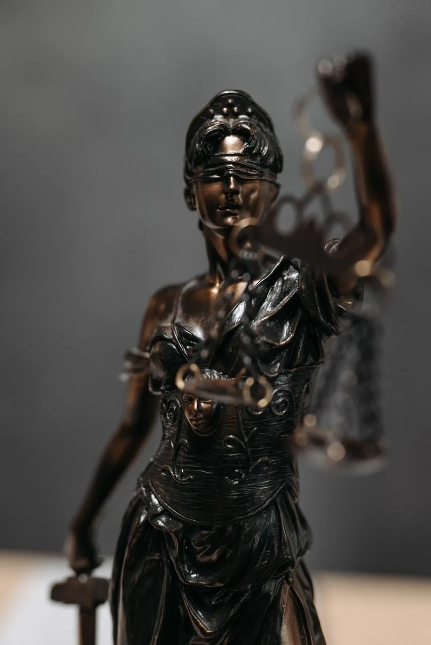 A bronze Lady Justice statue holding a set of scales.