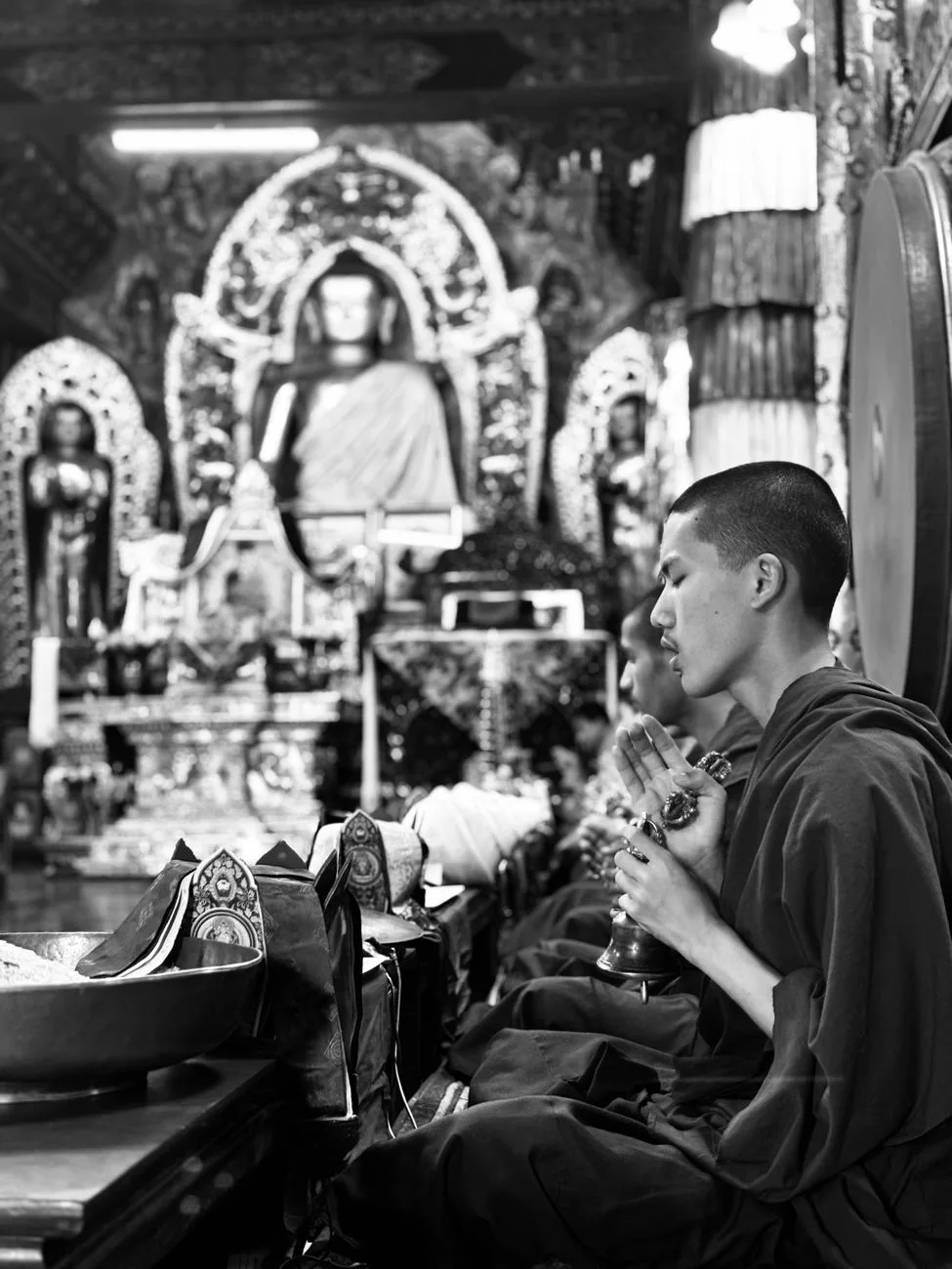 Monks in traditional robes praying in a serene Buddhist monastery.