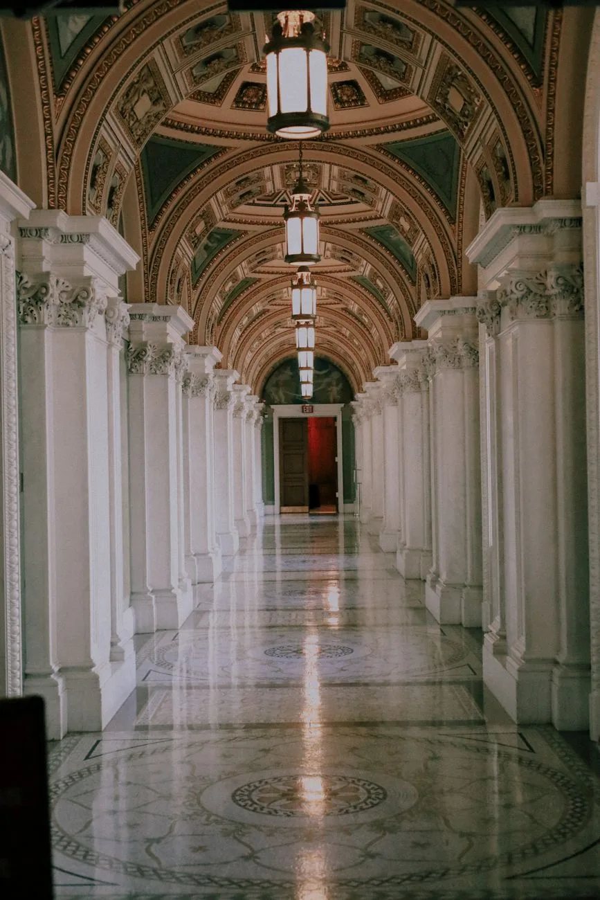 A luxurious corridor with marble floors and columns.