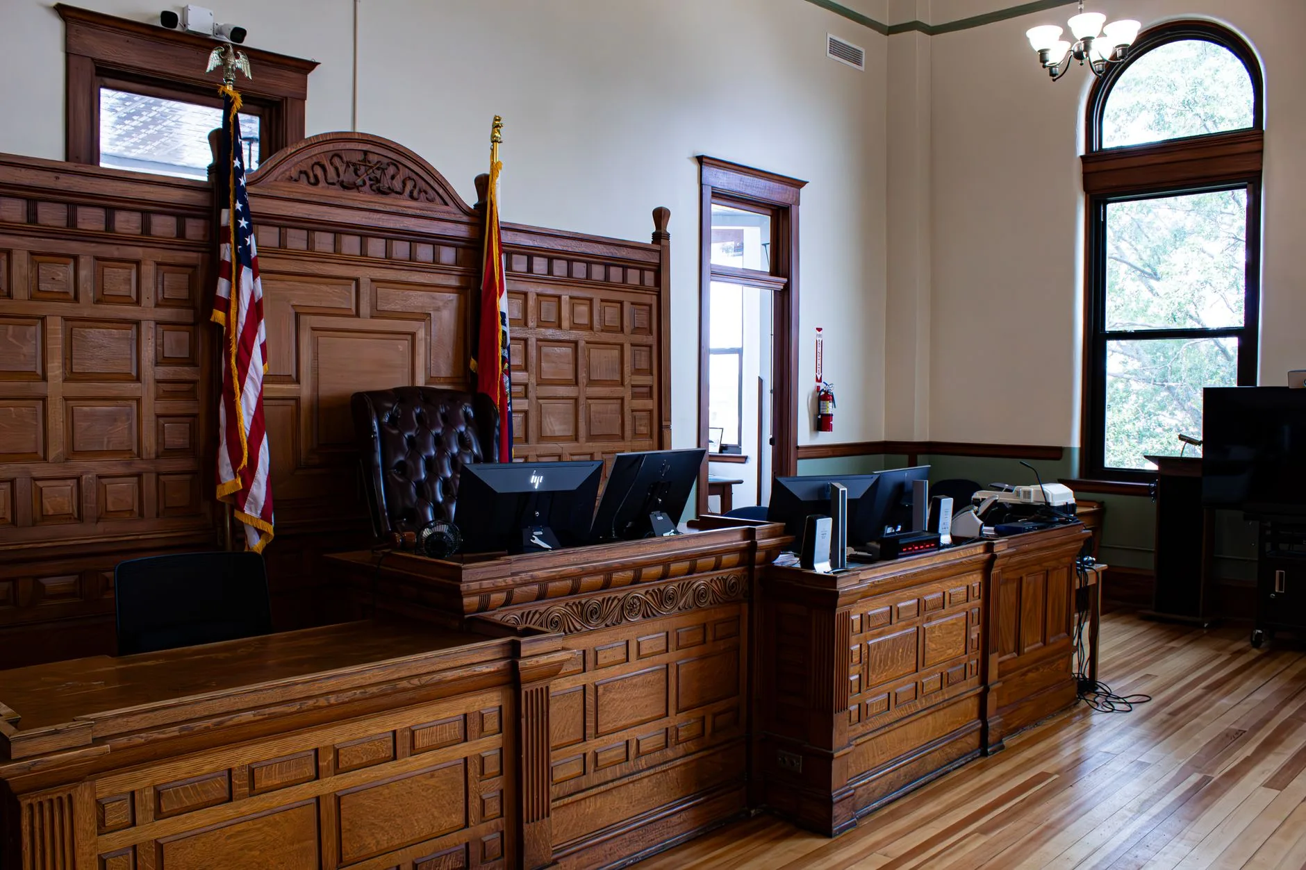 The interior of an American courthouse with a judicial desk and flags.