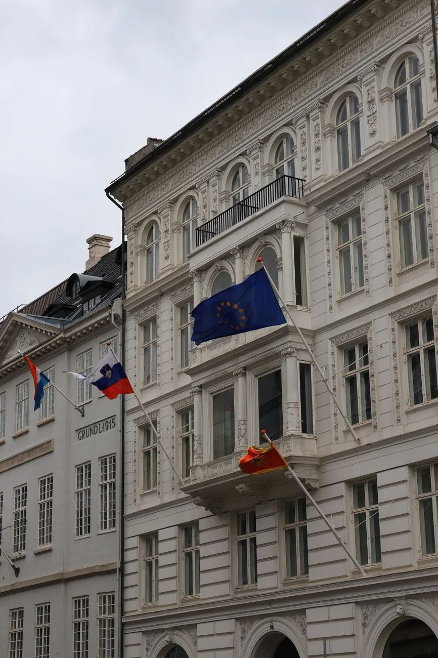 A historic building facade featuring multiple national flags.