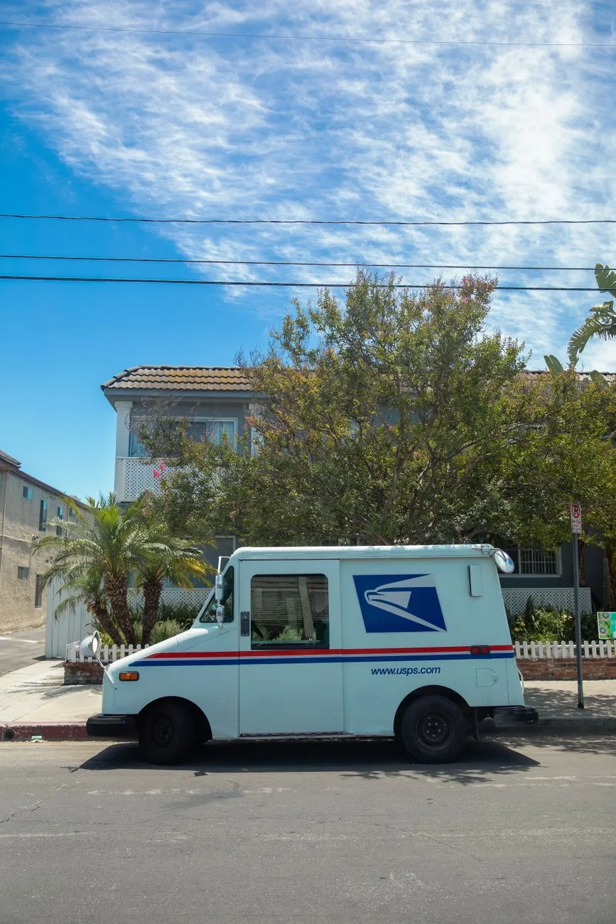 A white USPS delivery van parked in a residential street.