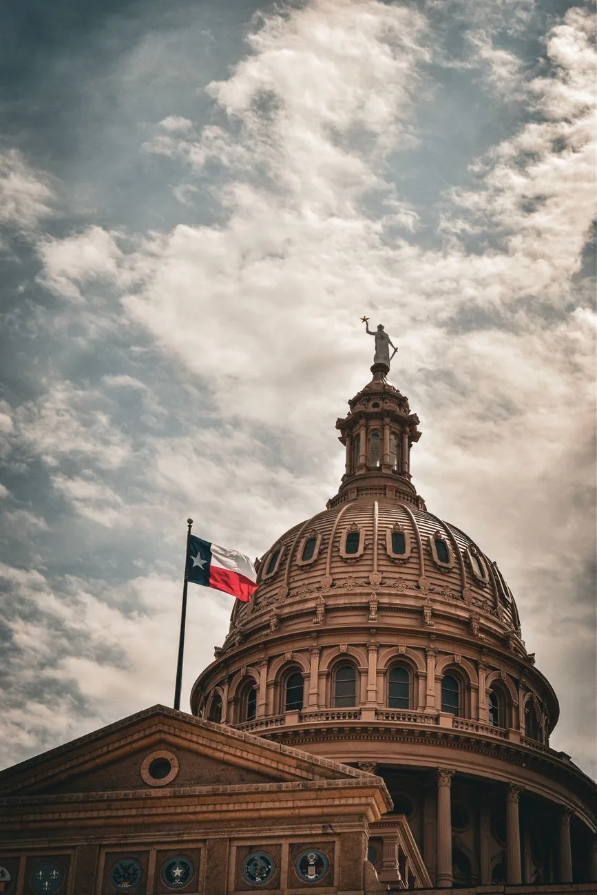 The dome of a state capitol building against a cloudy sky.