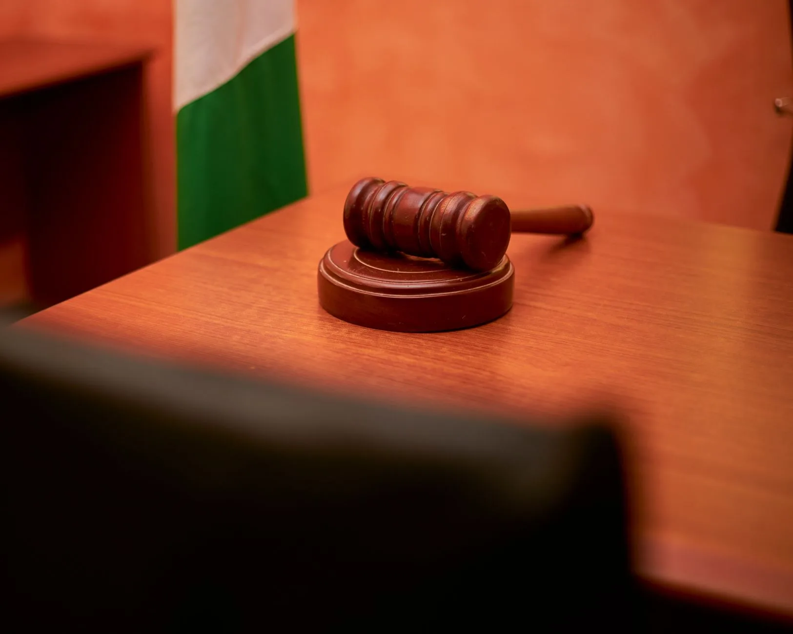 A close-up of a judicial gavel resting on a courtroom desk.
