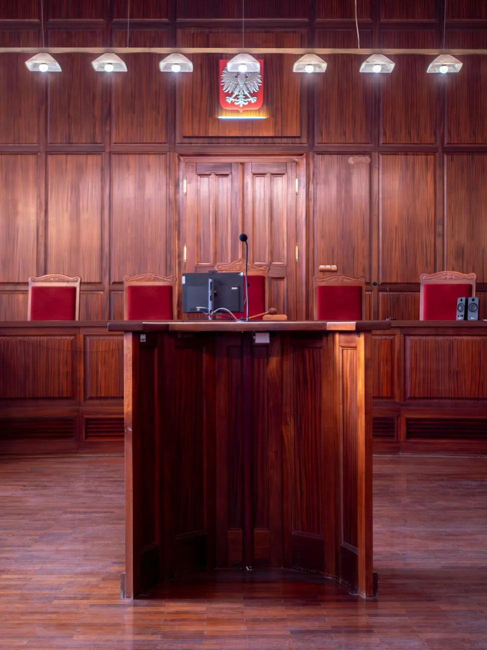 A polished wooden courtroom interior with a podium and seating.