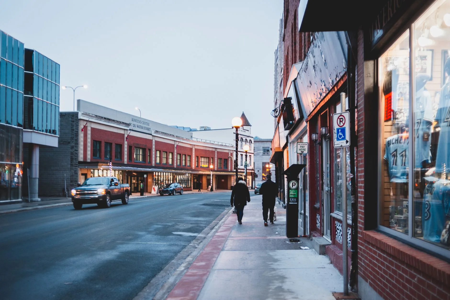 A lively downtown street with storefronts and pedestrians.