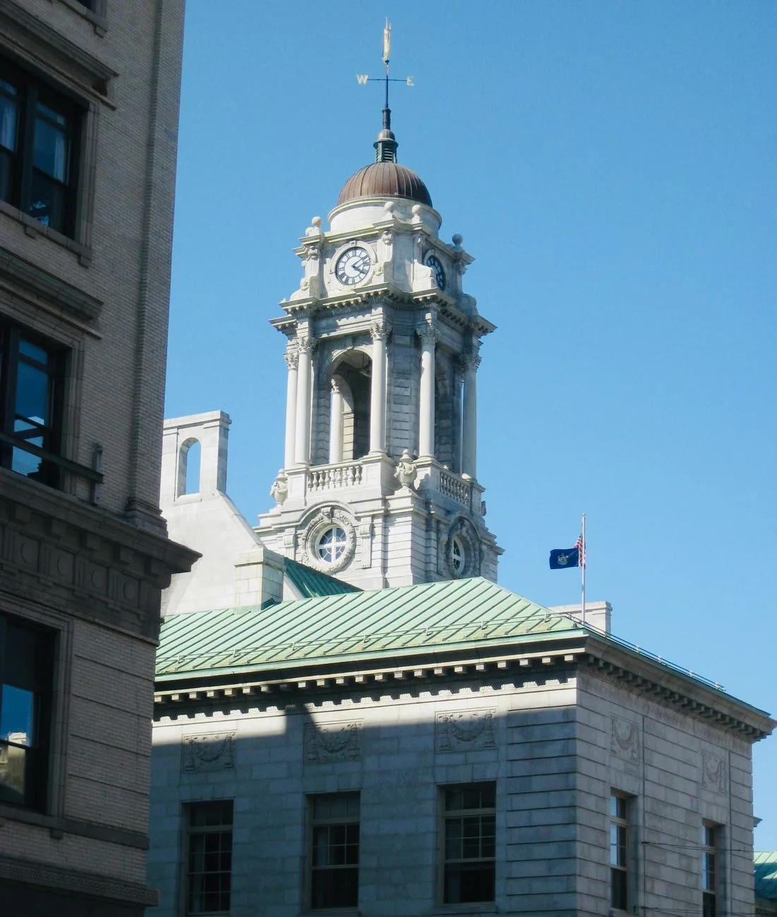 A historic city hall clock tower under a clear blue sky.