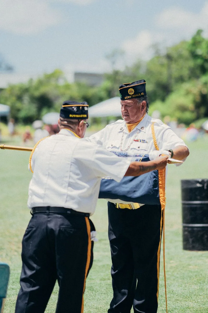 Two veterans folding an American flag during an outdoor ceremony.