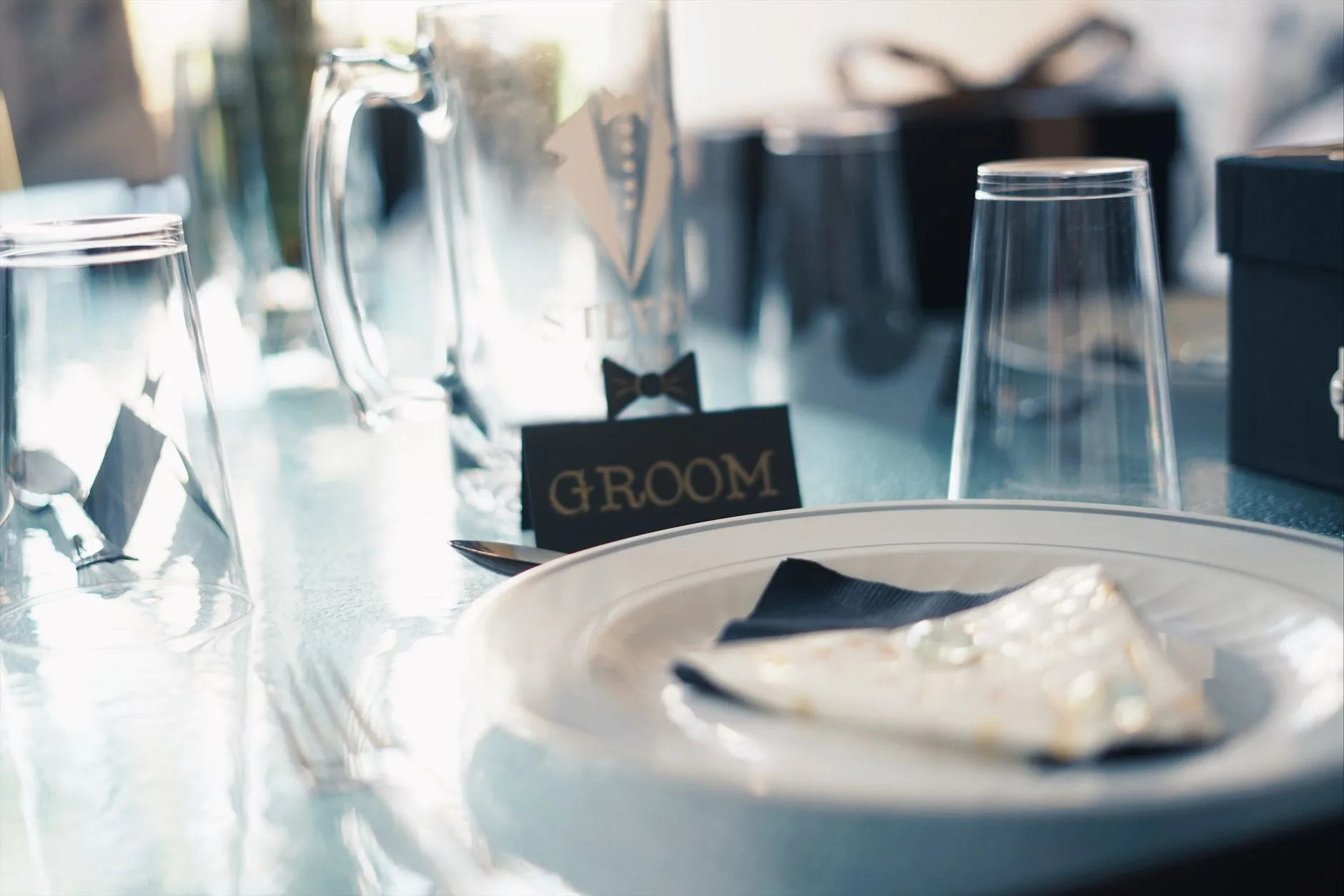 A wedding table setting featuring a place card, plates, and glassware.