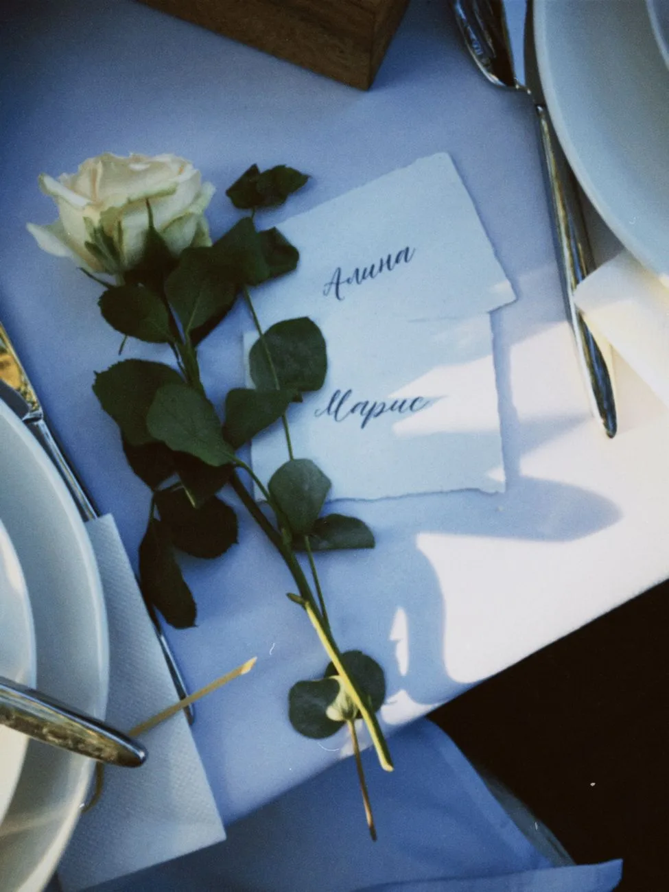 An elegant table setup with a white rose and personalized name cards.