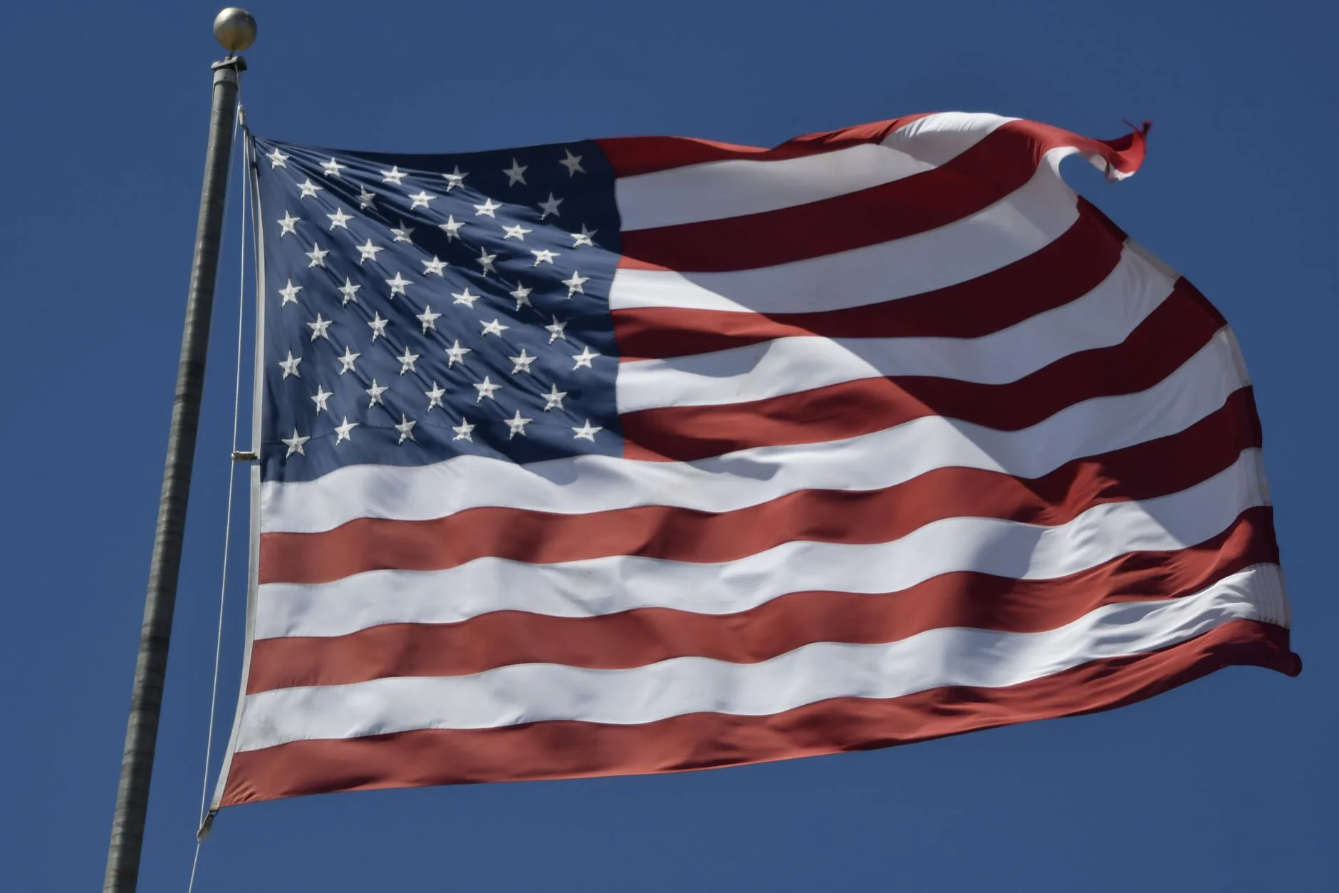 An American flag waving against a clear blue sky.