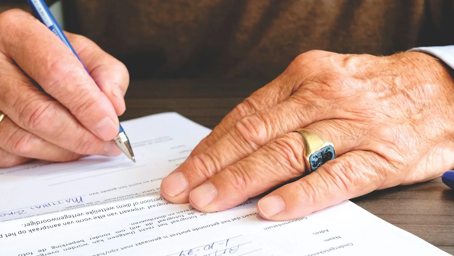 A close-up of a hand signing a formal document with a pen.