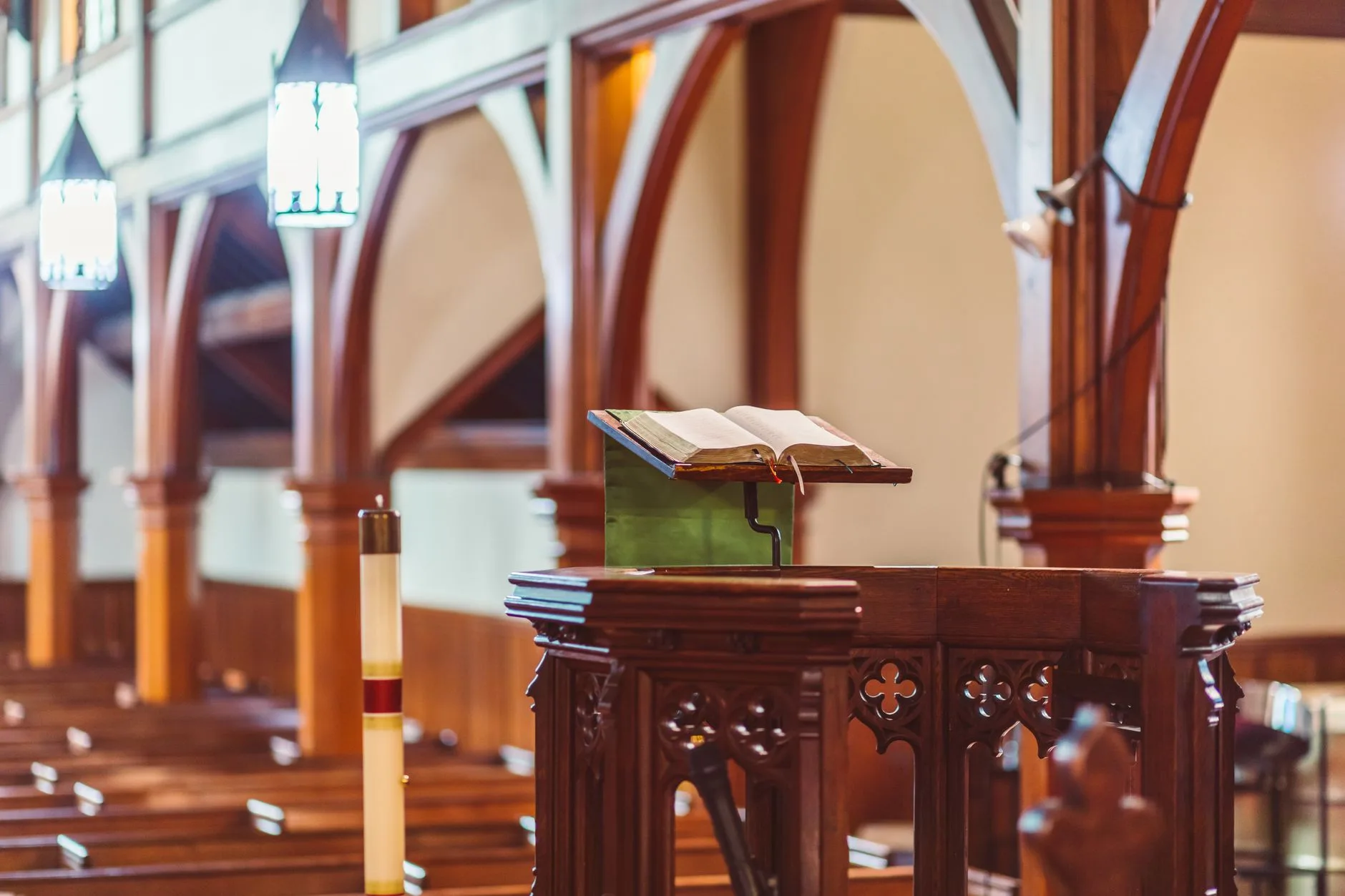 A wooden pulpit with an open Bible in an empty church.