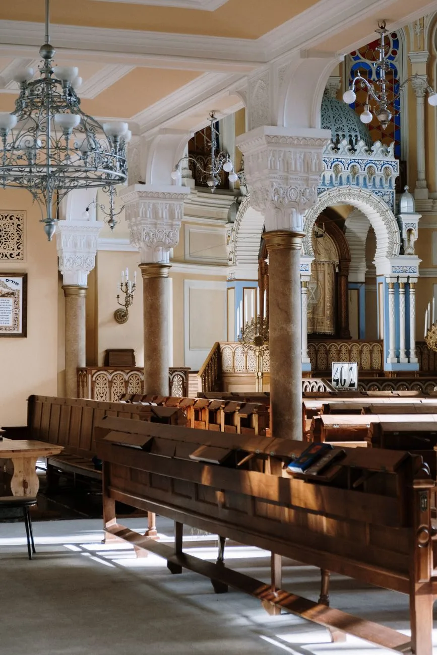 Wooden benches near the Torah ark in an ornate synagogue interior.
