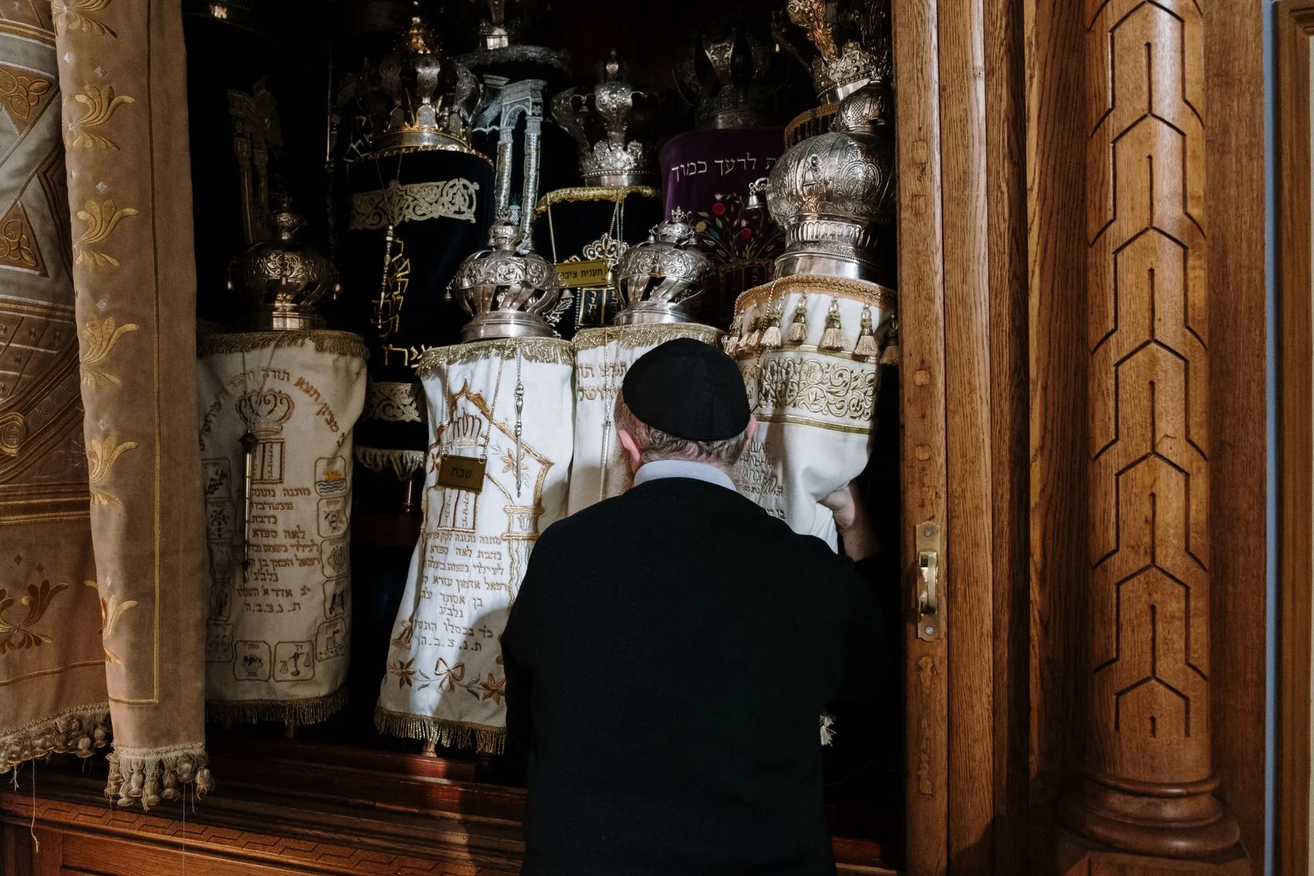 A rabbi standing before the Torah ark in a synagogue, holding the scrolls.