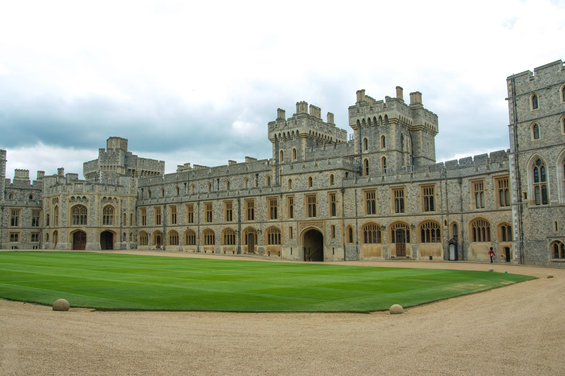 The grand architecture and courtyard of Windsor Castle on a cloudy day.