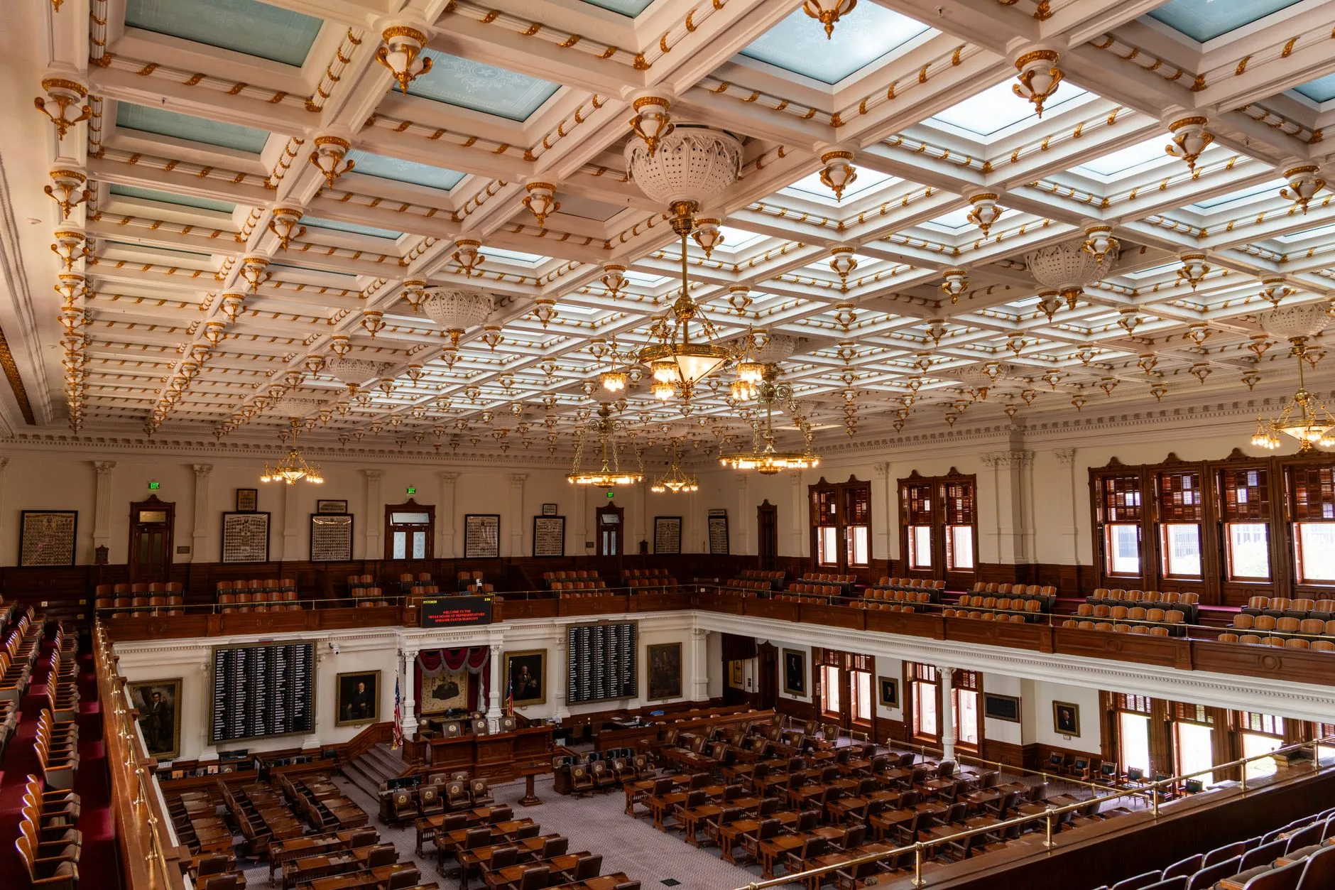 An ornate legislative chamber ceiling and empty seating.