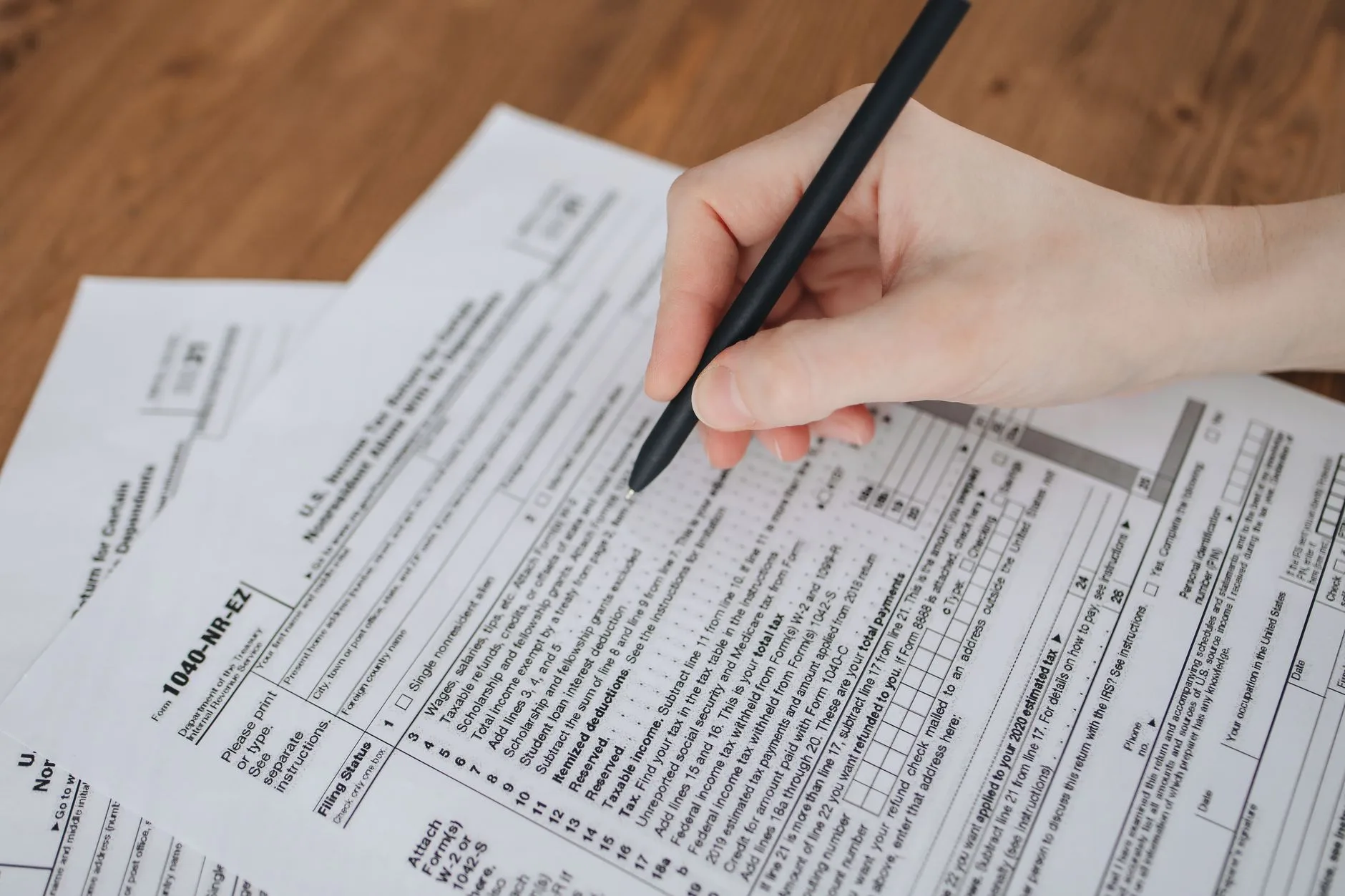 A close-up of a hand writing on official documents with a black pen.