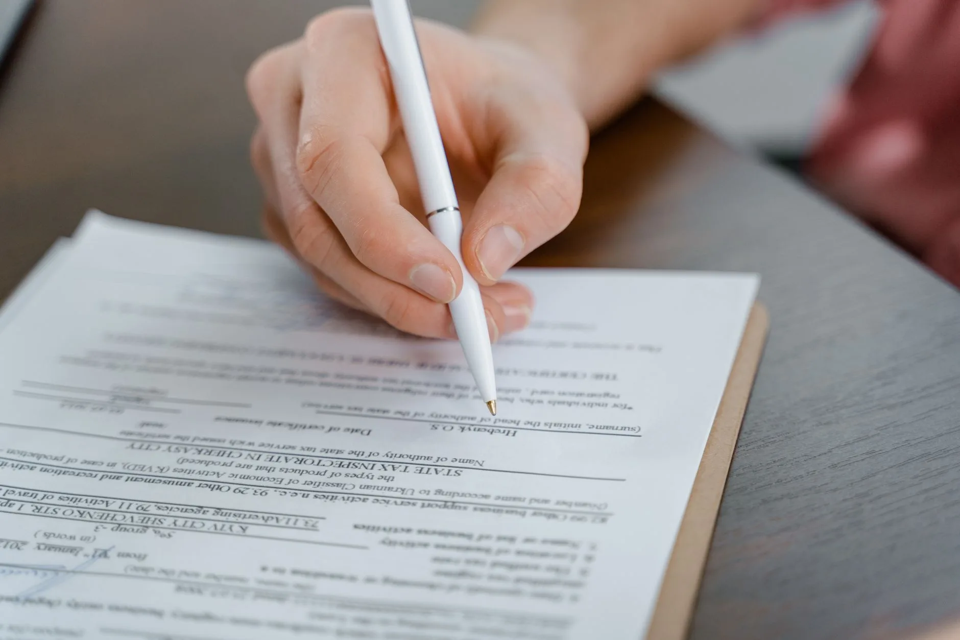 A hand holding a pen while signing a document.