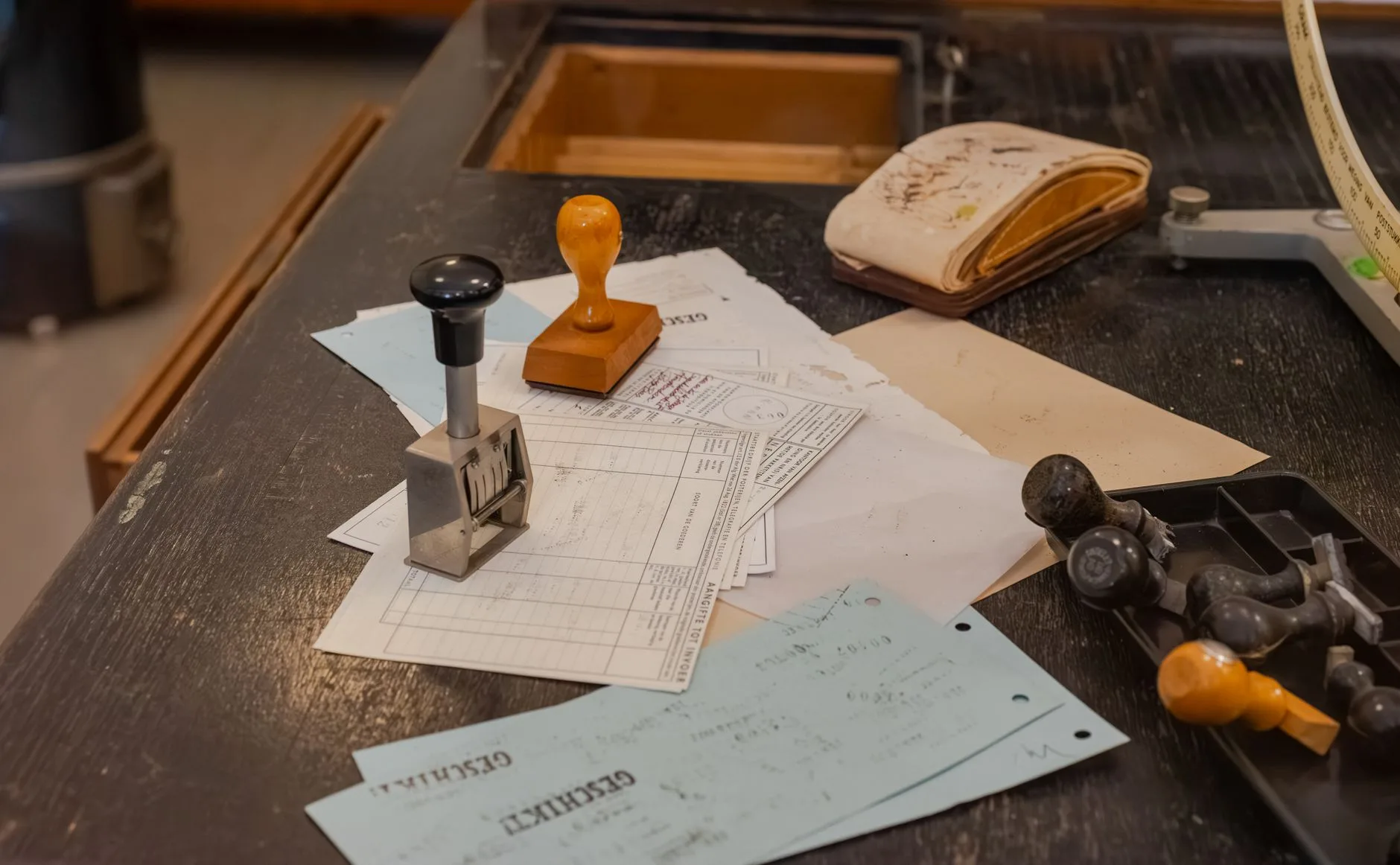 A cluttered office desk with stamps and documents.