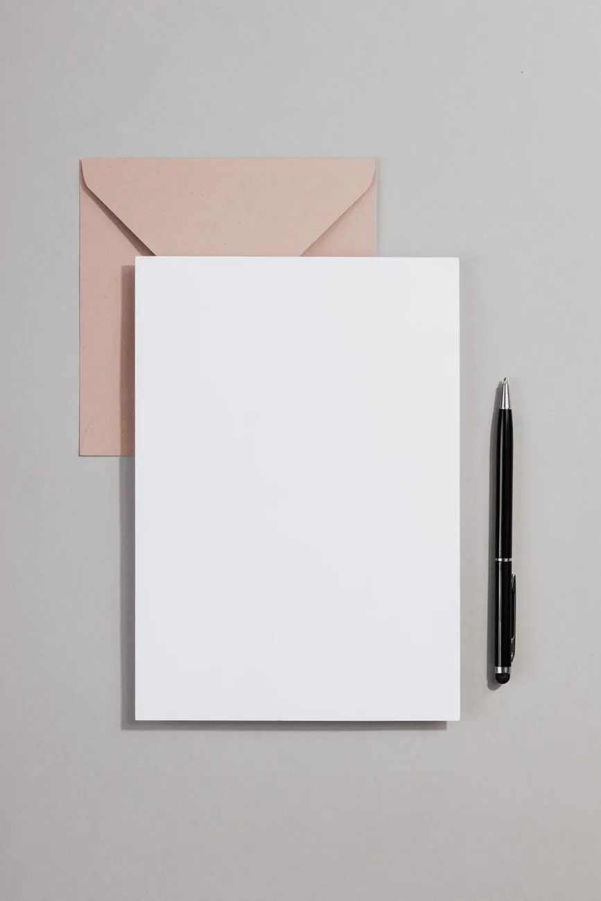 A minimalist stationery layout with a blank card, envelope, and pen.