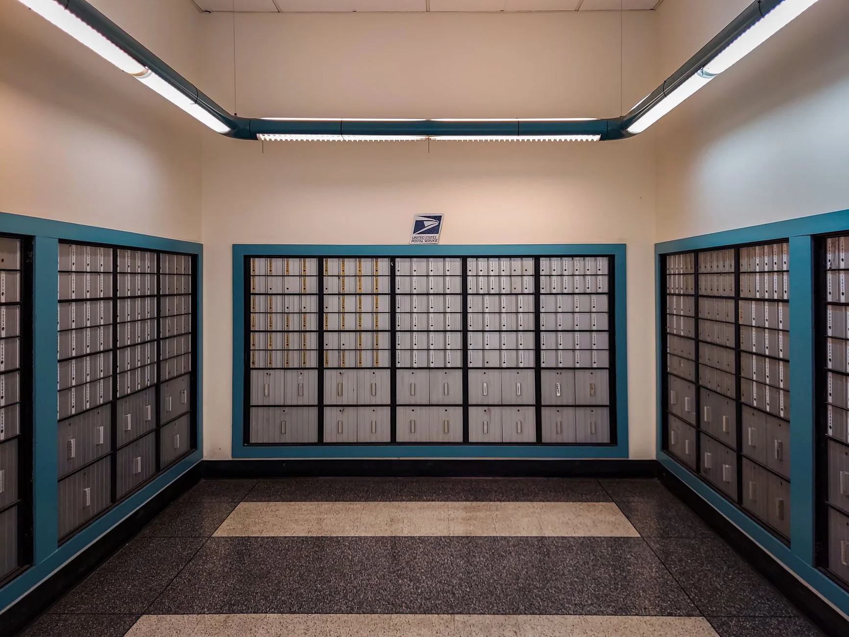 Rows of locked postal mailboxes in a post office interior.