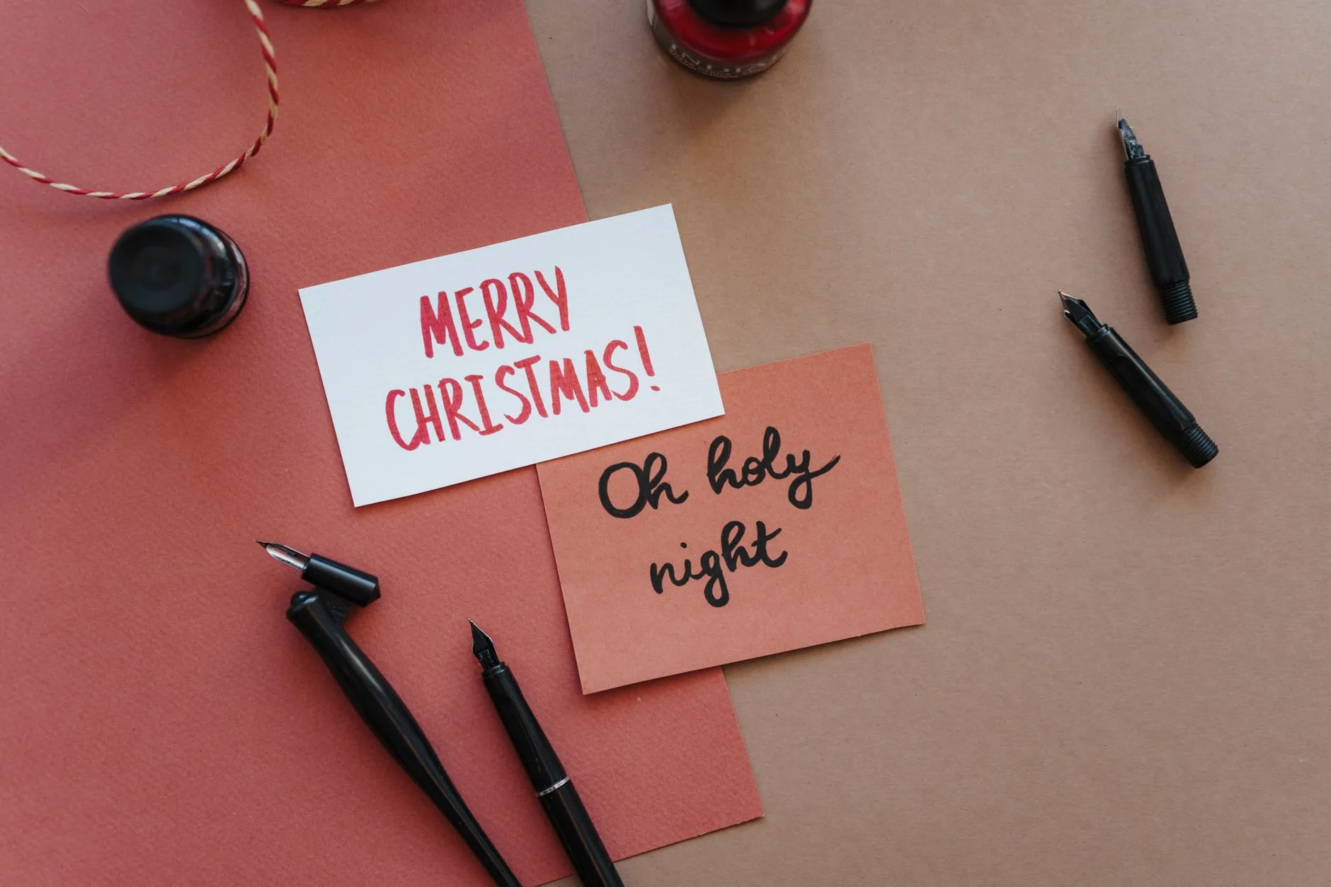 An elegant flat lay of handwritten Christmas cards with fountain pens and ink.