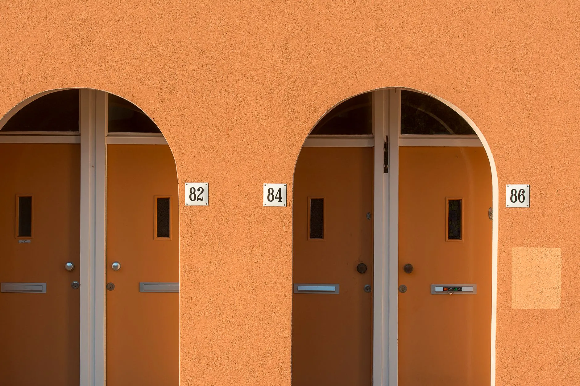 Stylish apartment doors with arched frames and house numbers.