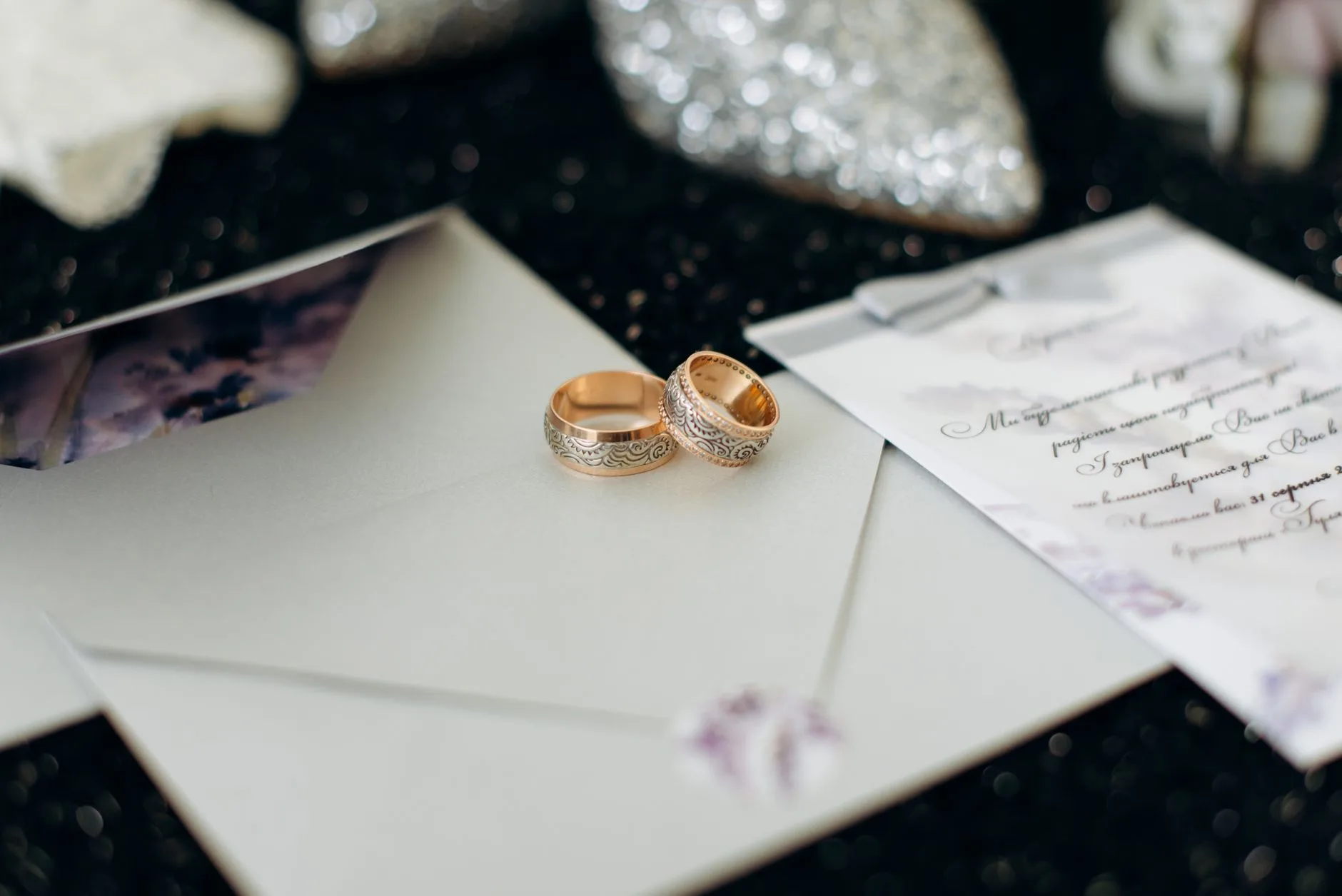 A close-up of elegant wedding rings placed on wedding invitation cards.