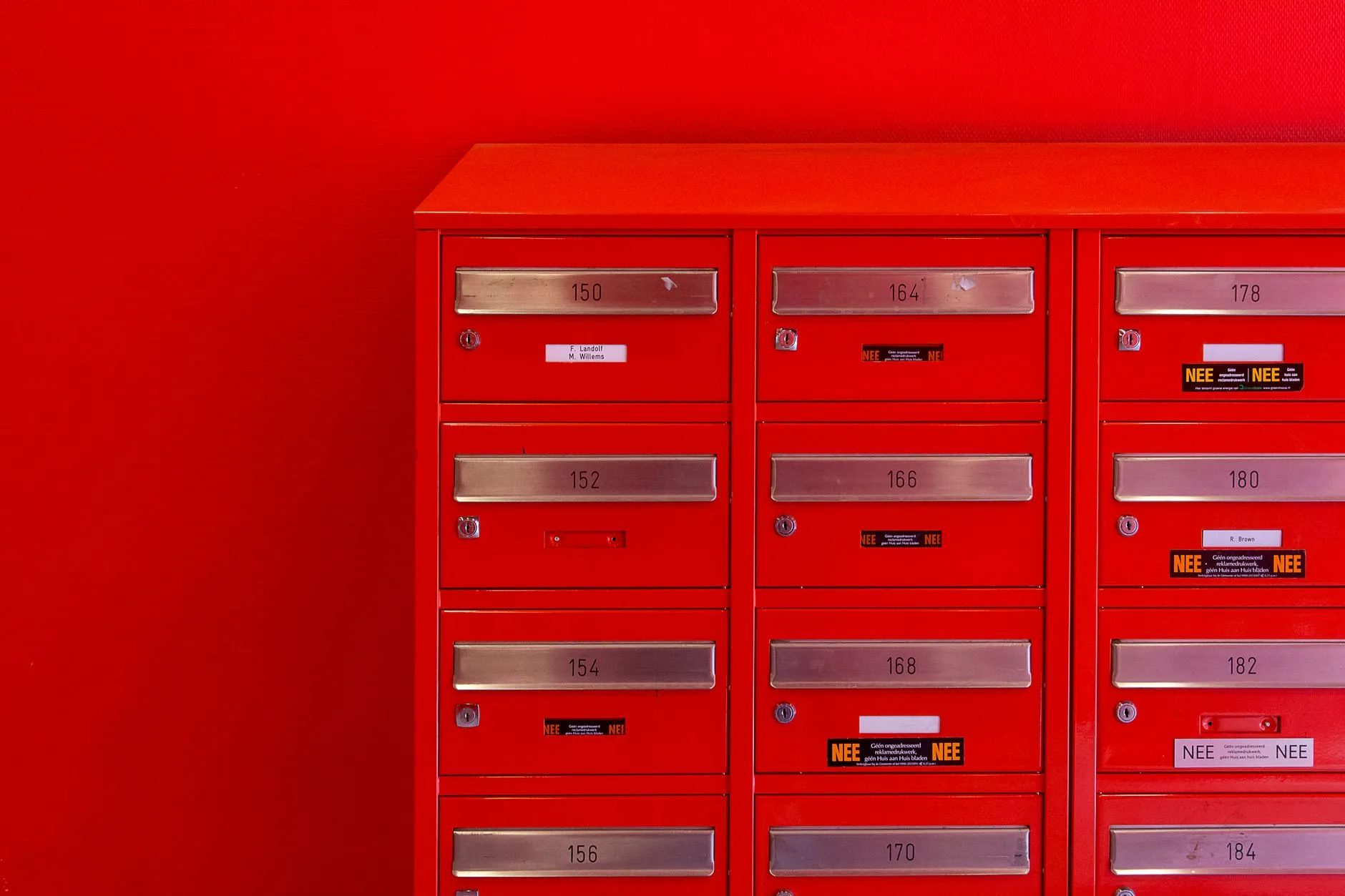 A row of sleek red mailboxes with metallic number panels.