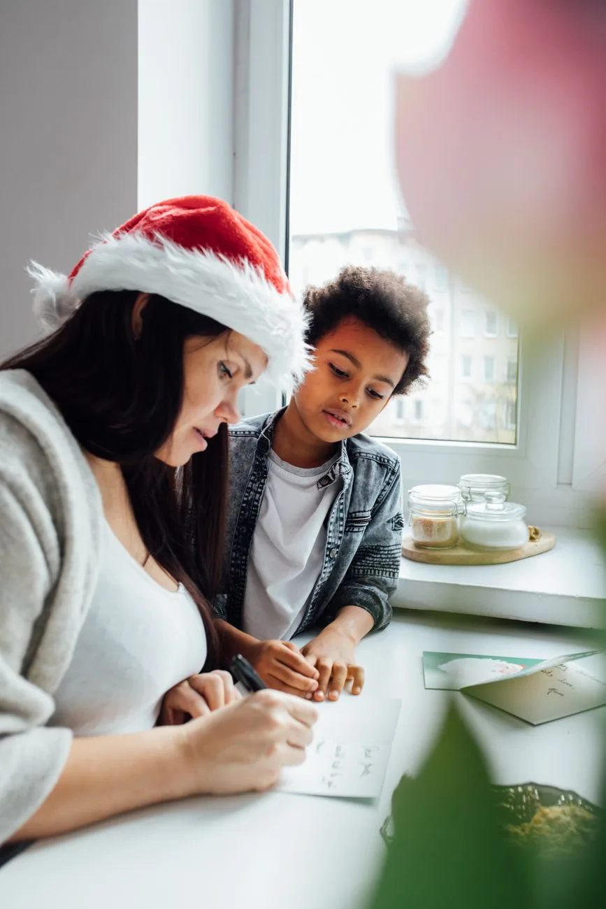 A parent and child writing cards together at home.