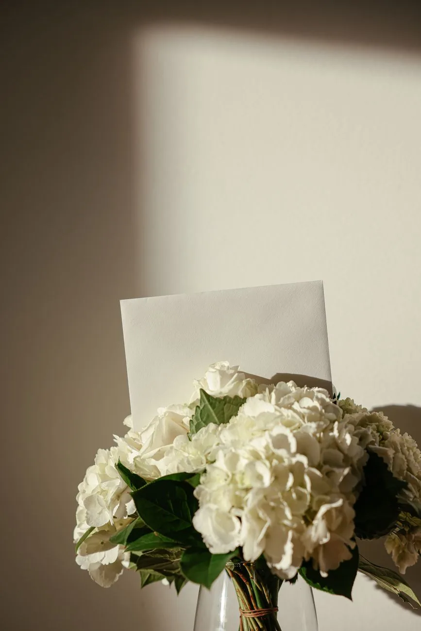 A bouquet of white flowers with a blank card, bathed in warm sunlight.