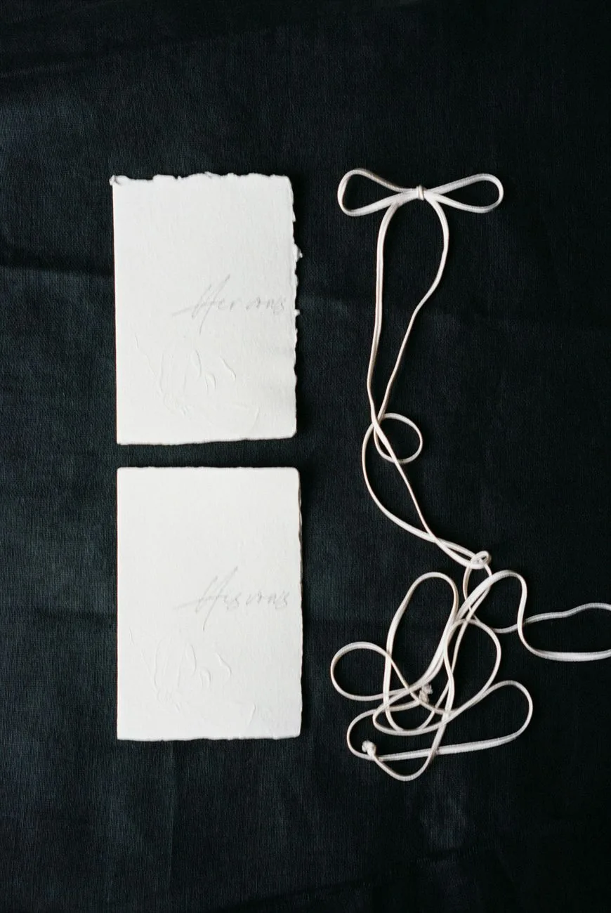An elegant black and white stationery flat lay with minimalist paper texture.