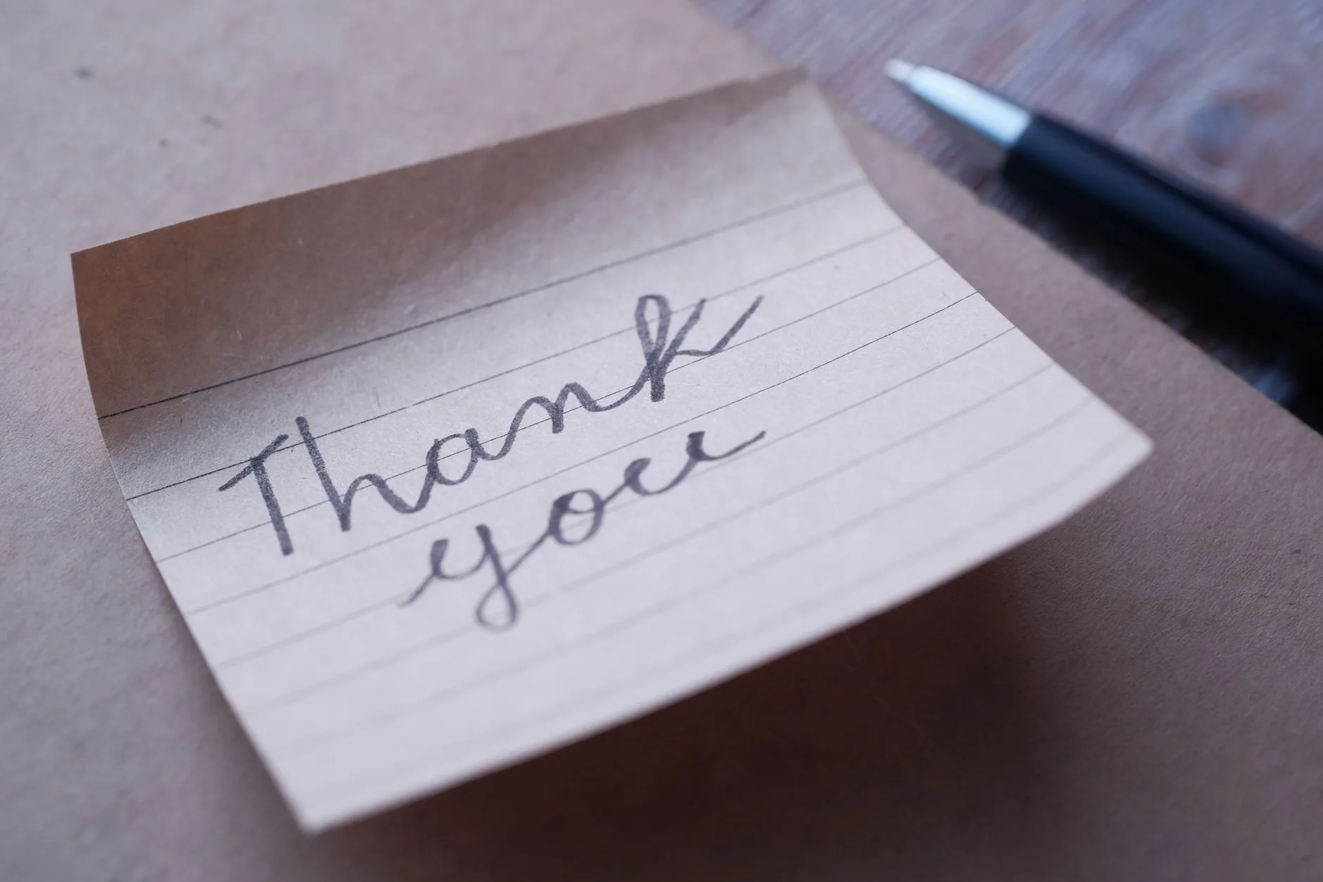 A close-up of a handwritten thank you note on brown paper.