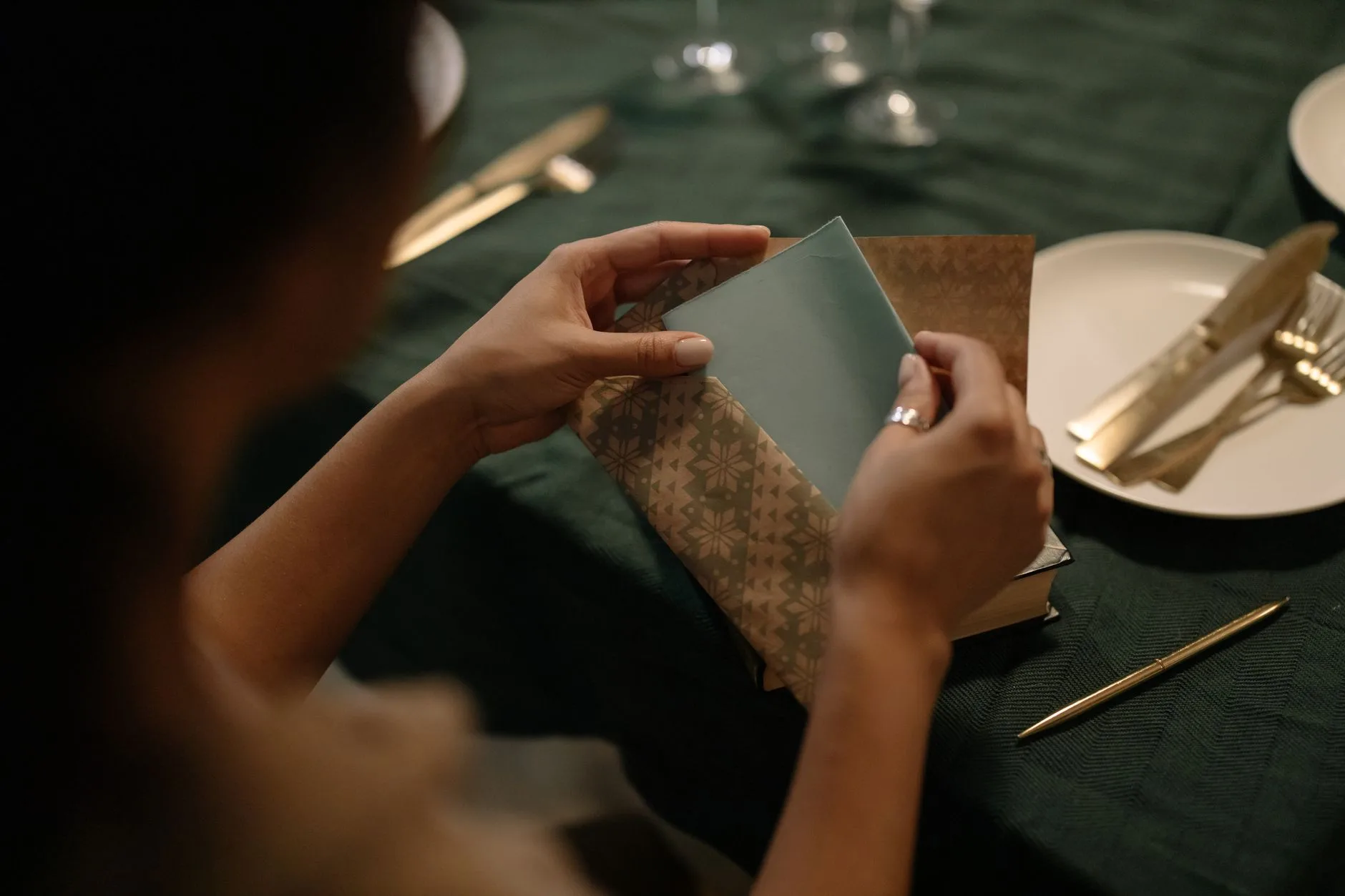 A close-up of a woman inserting a folded letter into an envelope.
