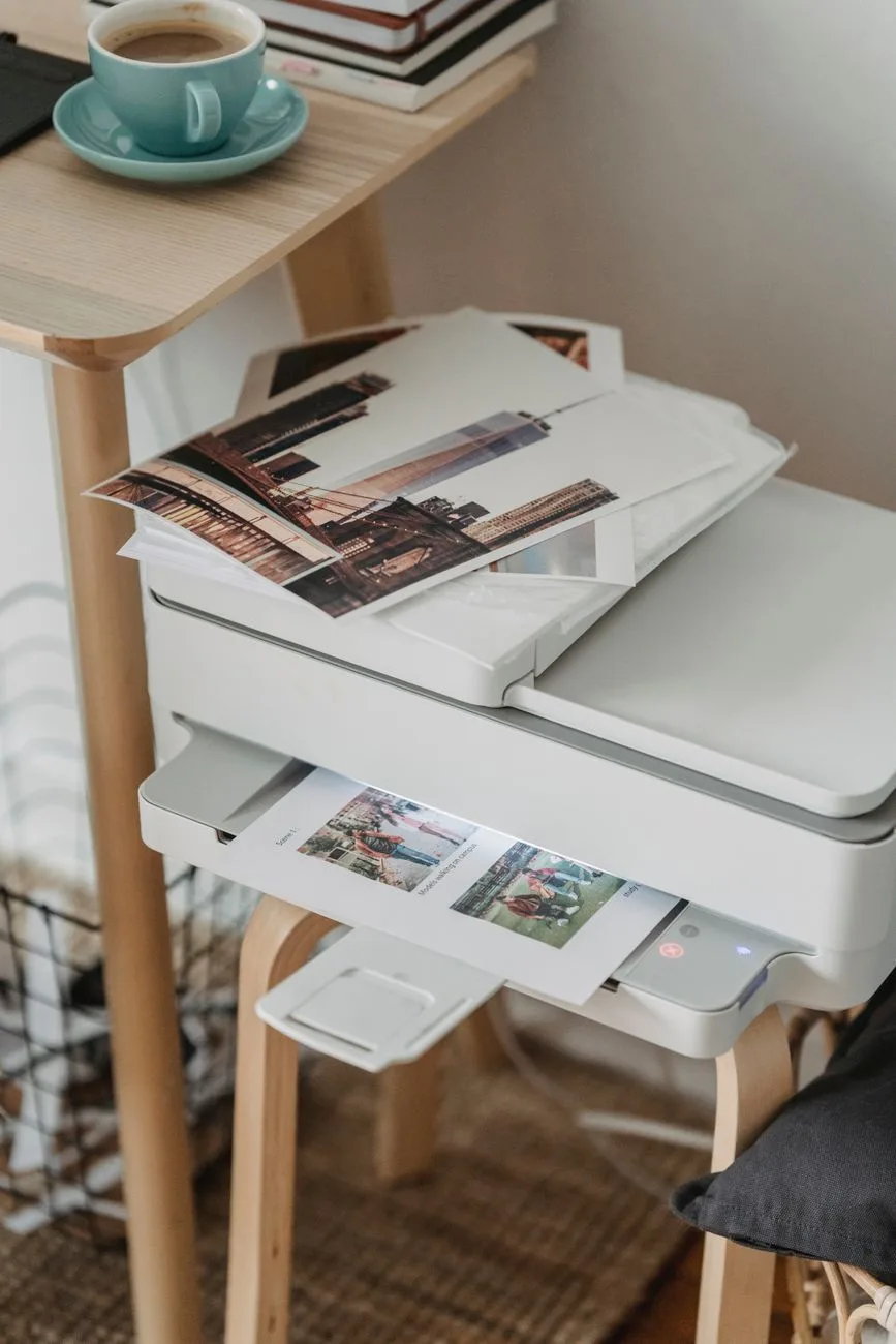 Printed pages next to a printer with a cup of coffee at a workplace.