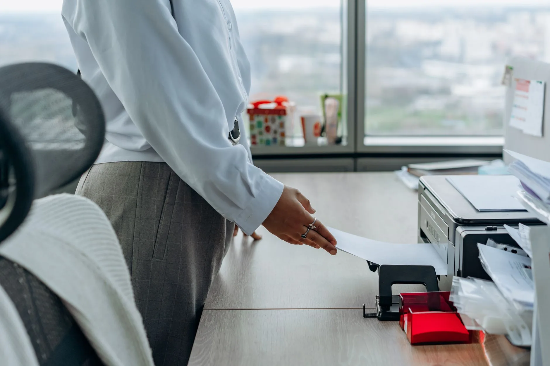 A business professional printing a document in an office environment.