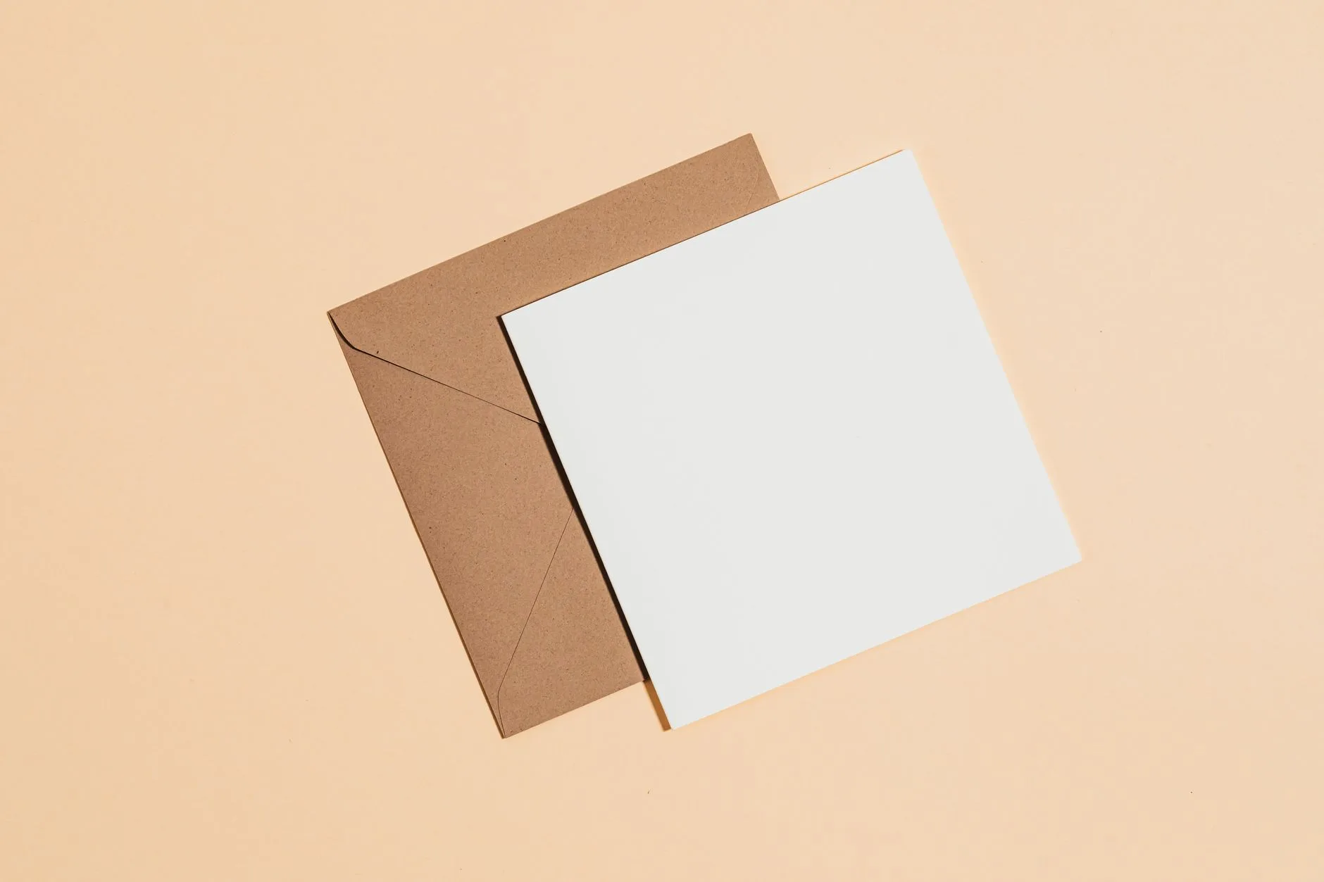 A minimalist flat lay of a brown envelope with a blank card on a pastel background.
