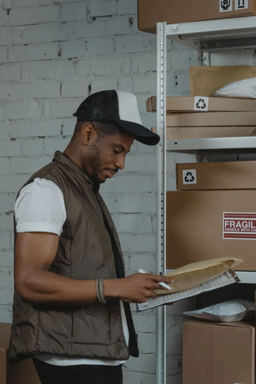 A postal worker sorting packages and mail in a warehouse.