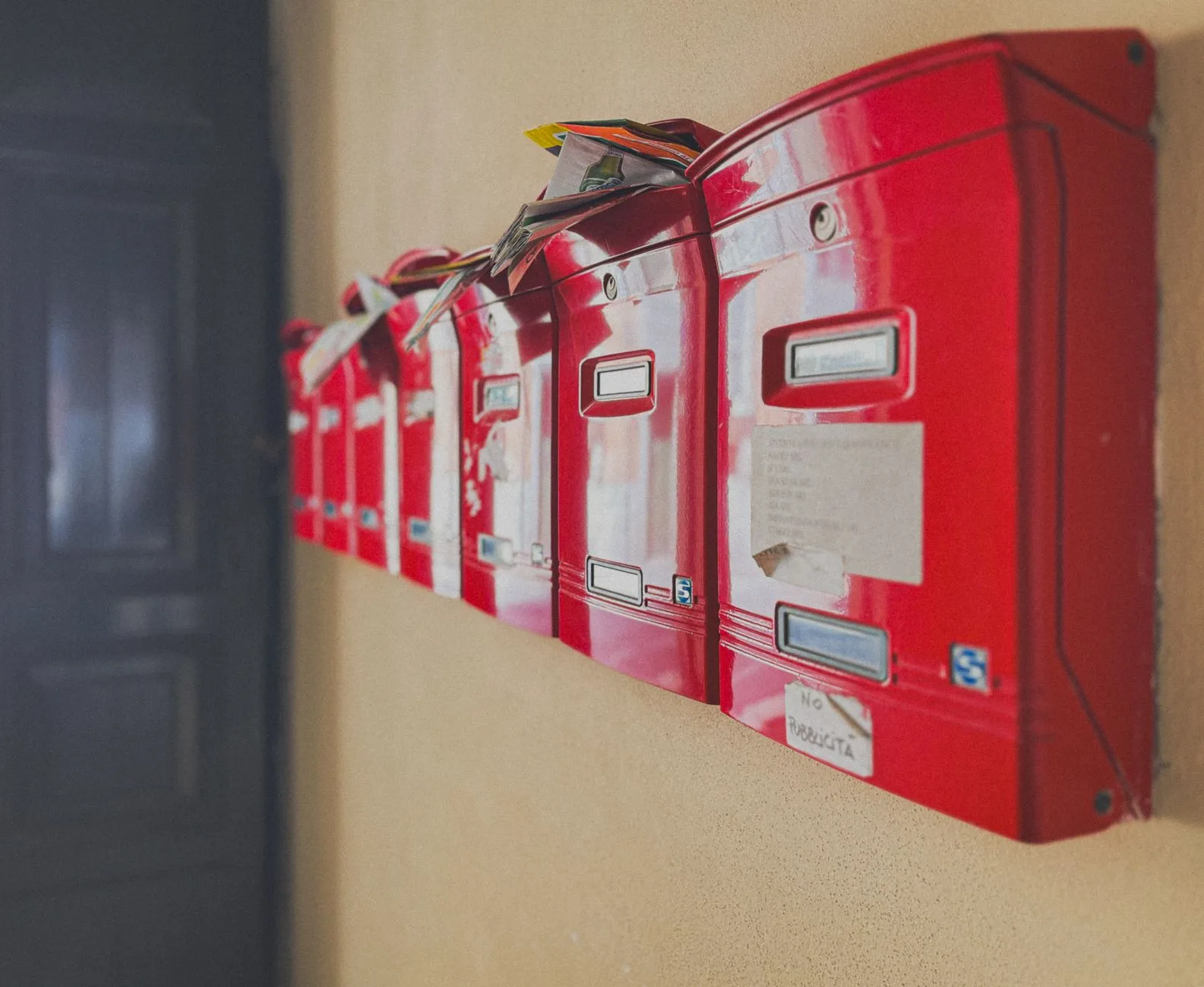 Row of mailboxes with mail overflowing out of them, undelivered and piling up.