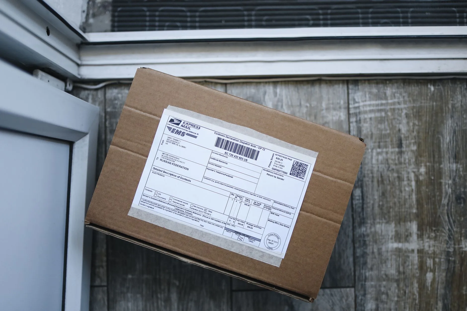 A cardboard shipping box with an address label, ready for delivery by the front door.