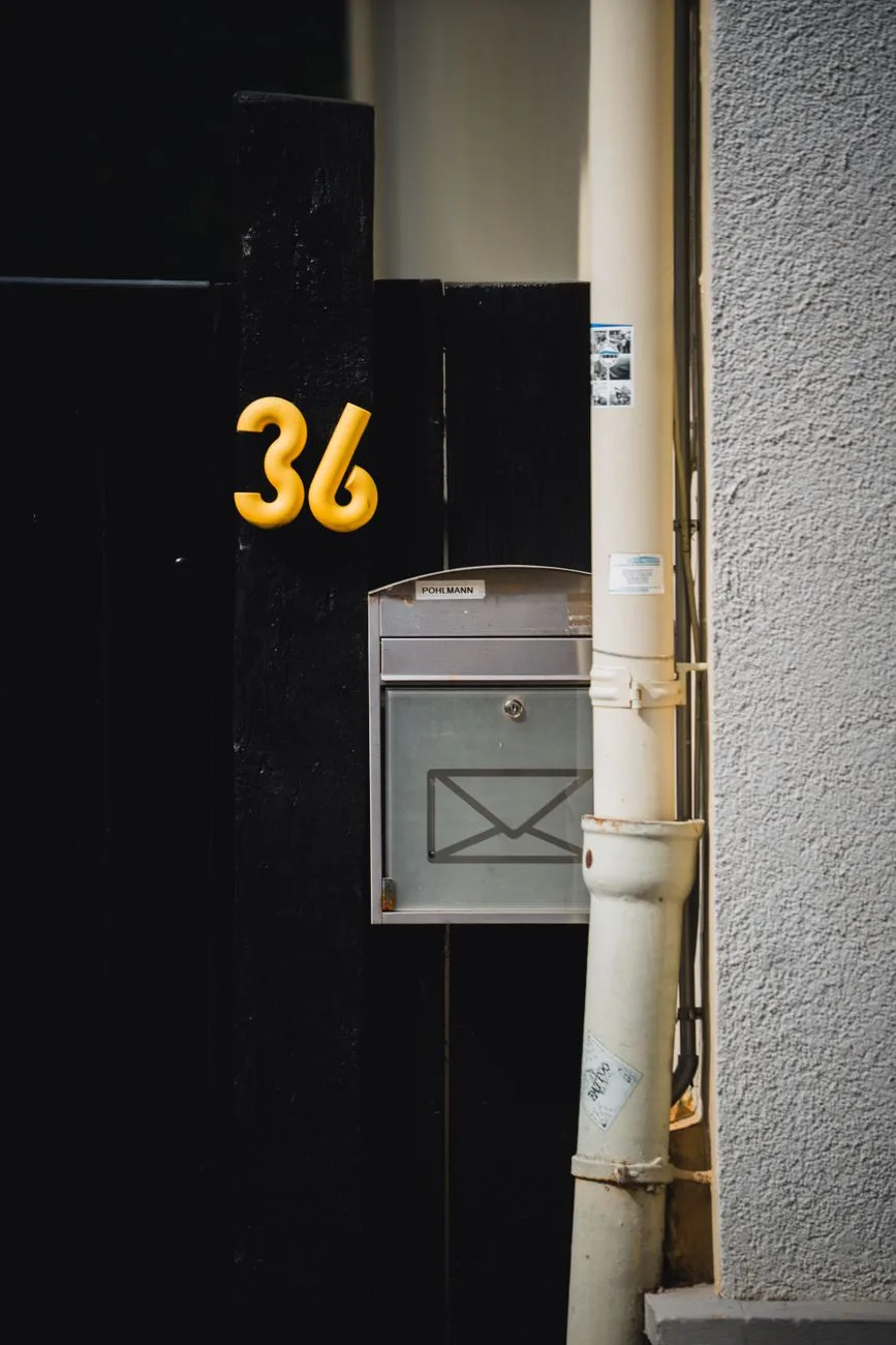 A modern house entrance with a mailbox mounted beside a bold house number.