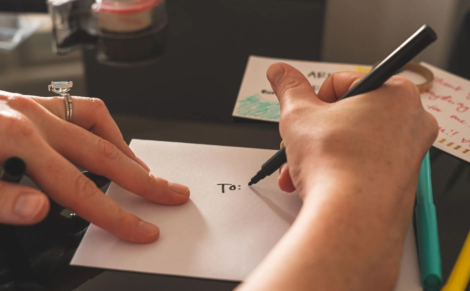 Hands writing an address on an envelope by hand.